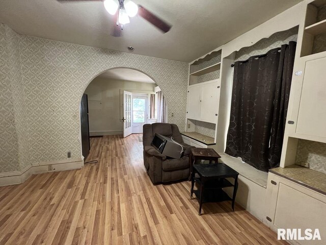 102 W 1st St, Table Grove, IL 61482 - sitting room featuring wallpapered walls, arched walkways, light wood finished floors, a ceiling fan, and baseboards