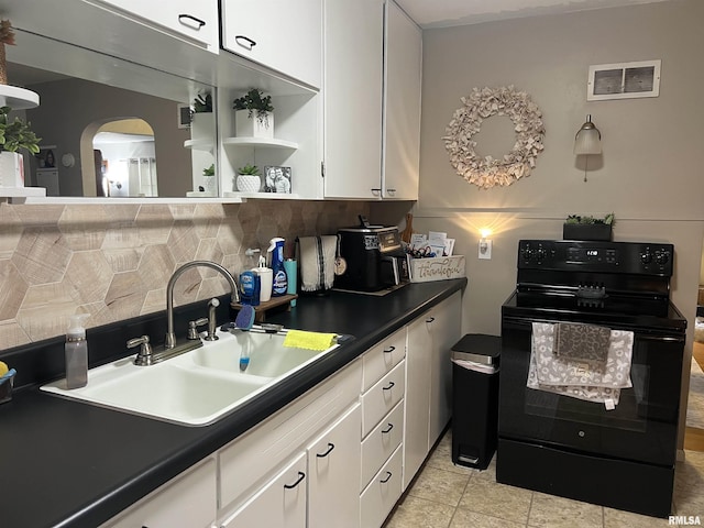 313 N Edwards St, Macomb, IL 61455 - kitchen featuring electric range, a sink, arched walkways, white cabinets, and backsplash