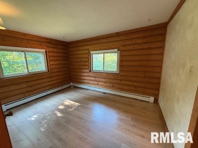 1 Marty Ln, Macomb, IL 61455 - unfurnished bedroom with log walls, a baseboard heating unit, a textured ceiling, carpet floors, and a closet