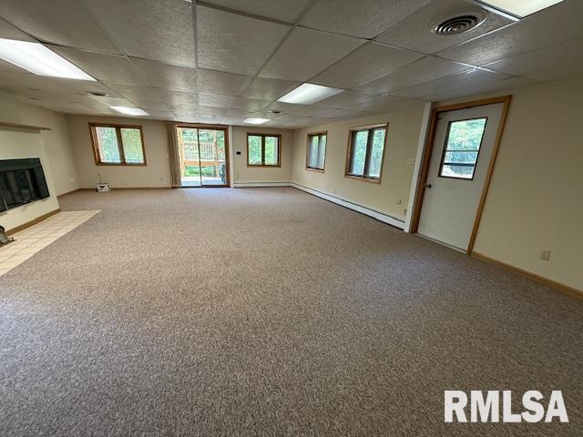 1 Marty Ln, Macomb, IL 61455 - below grade area with light colored carpet, a fireplace with flush hearth, a paneled ceiling, a baseboard heating unit, and baseboards