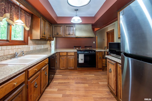 32 Black Partridge Run, Hopewell, IL 61565 - kitchen with black appliances, custom exhaust hood, brown cabinetry, light wood-style flooring, and light countertops