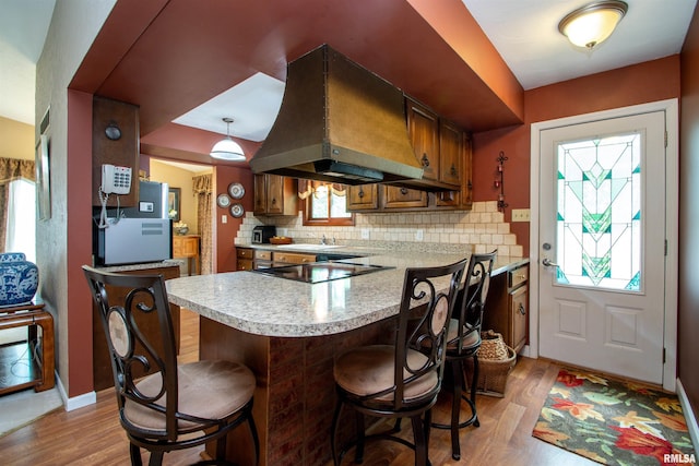32 Black Partridge Run, Hopewell, IL 61565 - kitchen featuring island range hood, light countertops, brown cabinetry, light wood-style floors, and decorative backsplash