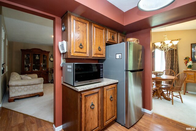 32 Black Partridge Run, Hopewell, IL 61565 - kitchen featuring freestanding refrigerator, a chandelier, brown cabinetry, and light wood-type flooring