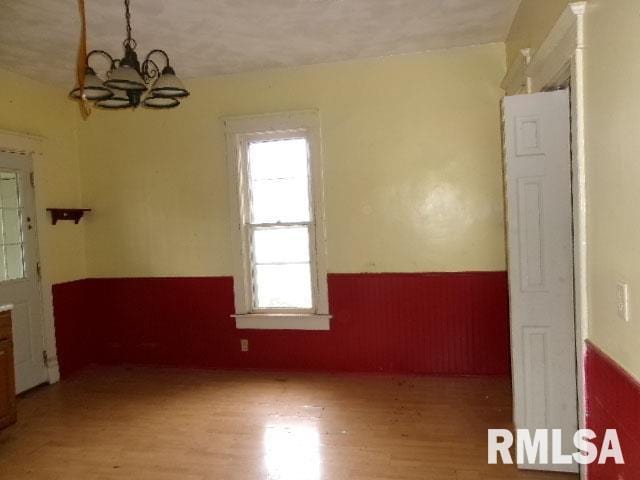 896 E Chestnut St, Canton, IL 61520 - spare room featuring a wainscoted wall, light wood finished floors, and a chandelier