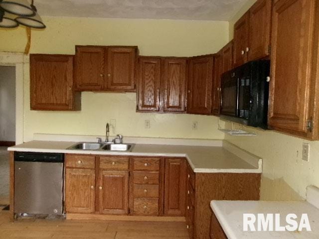896 E Chestnut St, Canton, IL 61520 - kitchen with stainless steel dishwasher, black microwave, a sink, brown cabinets, and light countertops