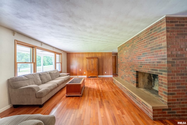 23907 Veterans Rd, Morton, IL 61550 - living room with light wood-type flooring, baseboards, a brick fireplace, a textured ceiling, and wooden walls