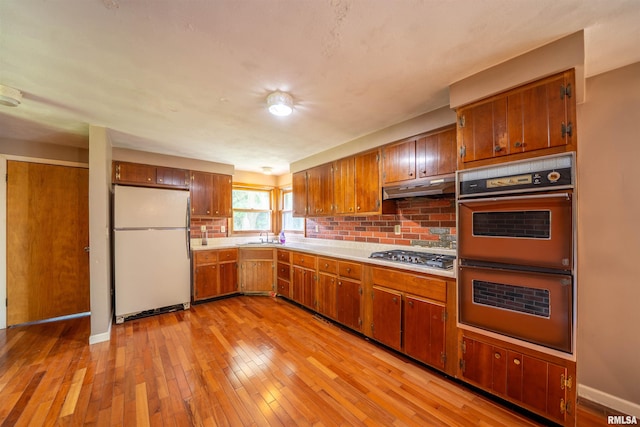 23907 Veterans Rd, Morton, IL 61550 - kitchen with freestanding refrigerator, multiple ovens, stainless steel gas stovetop, under cabinet range hood, and light countertops