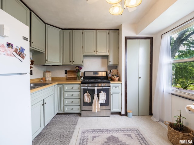 1402 Lincoln Rd, Marquette Heights, IL 61554 - kitchen featuring freestanding refrigerator, stainless steel range with gas stovetop, light countertops, and light tile patterned floors