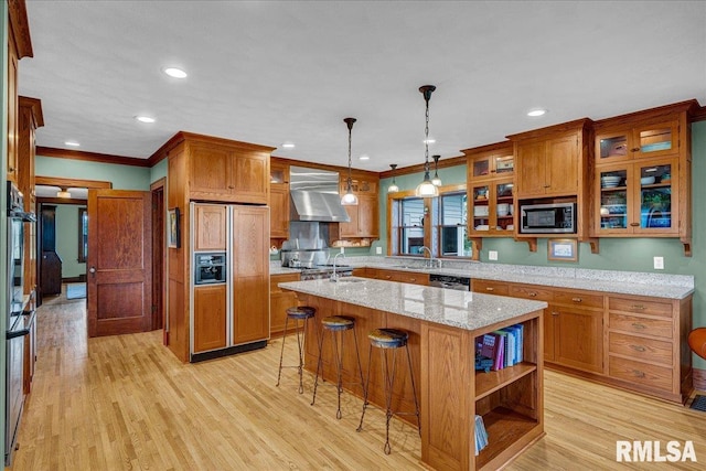701 E Pearl St, Tremont, IL 61568 - kitchen with built in appliances, wall chimney range hood, brown cabinets, a kitchen island with sink, and crown molding