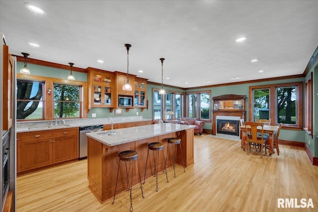 701 E Pearl St, Tremont, IL 61568 - kitchen featuring stainless steel appliances, light wood-style flooring, a fireplace with flush hearth, brown cabinetry, and ornamental molding
