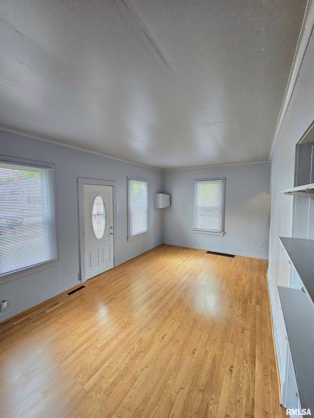 723 E Maywood Ave, Peoria, IL 61603 - unfurnished living room featuring light wood-style flooring and a wall mounted air conditioner