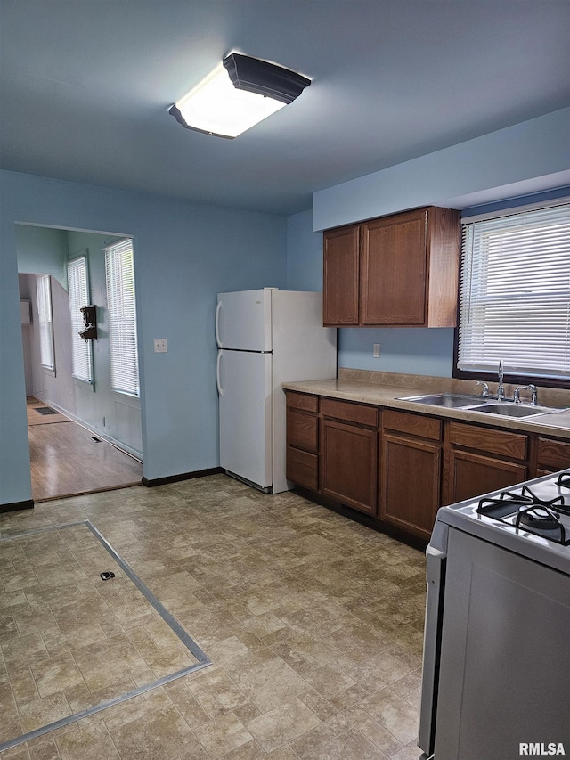 723 E Maywood Ave, Peoria, IL 61603 - kitchen with white appliances, a sink, brown cabinetry, and baseboards