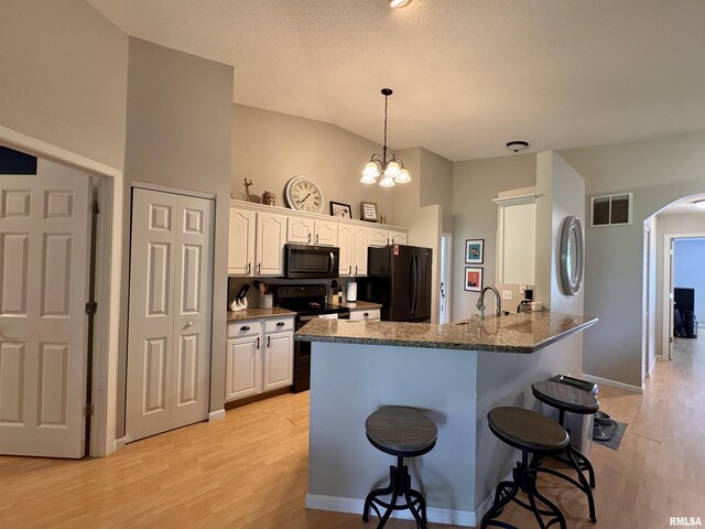 1041 Hawthorn Rdg, Macomb, IL 61455 - kitchen featuring black appliances, a kitchen breakfast bar, arched walkways, light wood-style floors, and a peninsula