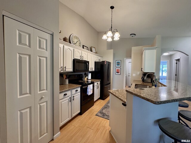 1041 Hawthorn Rdg, Macomb, IL 61455 - kitchen featuring black appliances, a sink, a kitchen breakfast bar, arched walkways, and light wood-type flooring