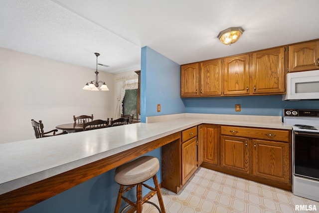 6500 N Allen Rd Unit 62, Peoria, IL 61614 - kitchen with white appliances, brown cabinets, a breakfast bar, and a chandelier