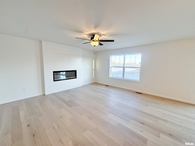 4014 W Fiona Way, Dunlap, IL 61525 - unfurnished living room featuring light wood-style floors, a large fireplace, and a ceiling fan