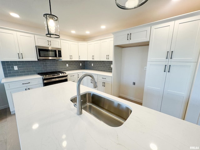 4014 W Fiona Way, Dunlap, IL 61525 - kitchen with stainless steel appliances, hanging light fixtures, white cabinets, tasteful backsplash, and light stone countertops