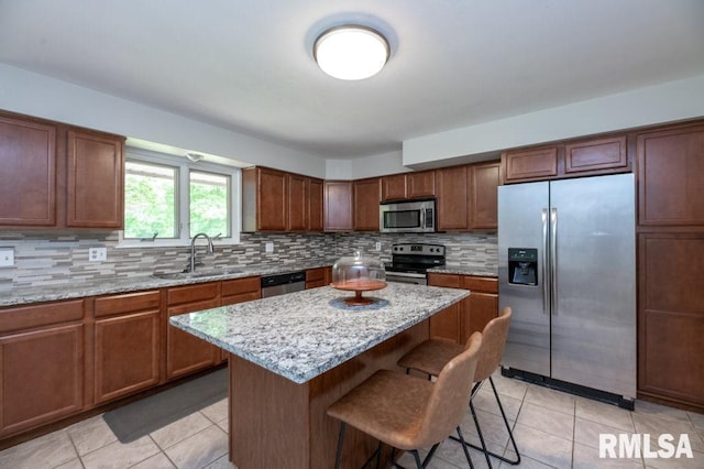 5232 N Merrimac Ave, Peoria, IL 61614 - kitchen with stainless steel appliances, a sink, light tile patterned floors, and a kitchen breakfast bar
