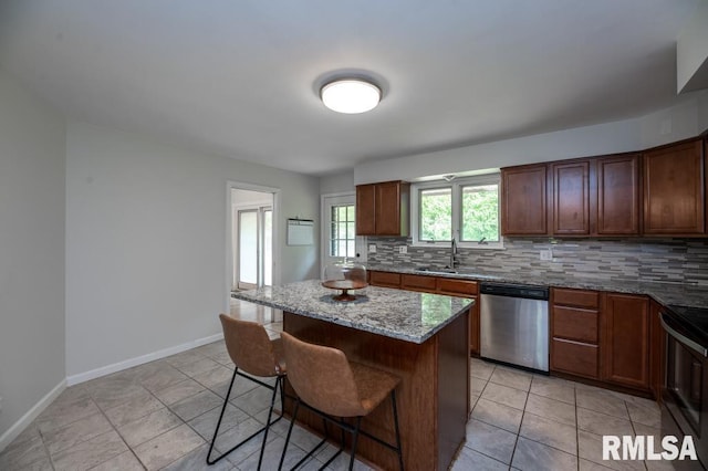 5232 N Merrimac Ave, Peoria, IL 61614 - kitchen with stainless steel dishwasher, tasteful backsplash, a kitchen breakfast bar, light stone countertops, and a sink
