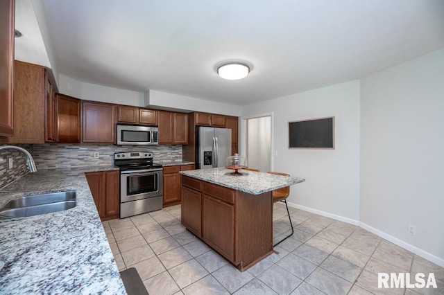 5232 N Merrimac Ave, Peoria, IL 61614 - kitchen featuring stainless steel appliances, a sink, decorative backsplash, a breakfast bar area, and light tile patterned floors