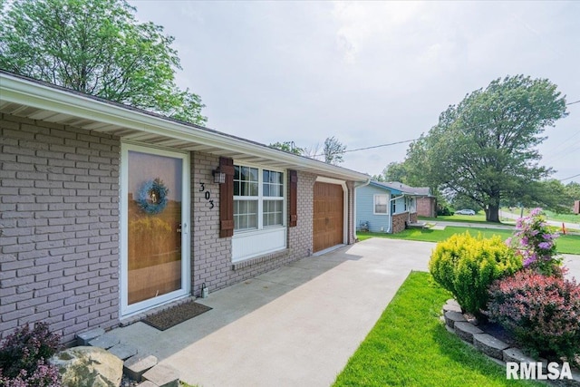 303 W 3rd Ave, Deer Creek, IL 61733 - doorway to property with driveway, brick siding, and an attached garage