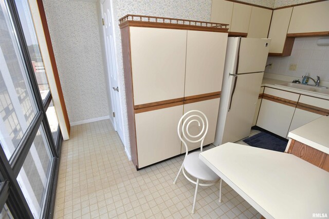 123 SW Jefferson Ave Unit E14A, Peoria, IL 61602 - kitchen with wallpapered walls, a sink, light countertops, freestanding refrigerator, and cream cabinetry
