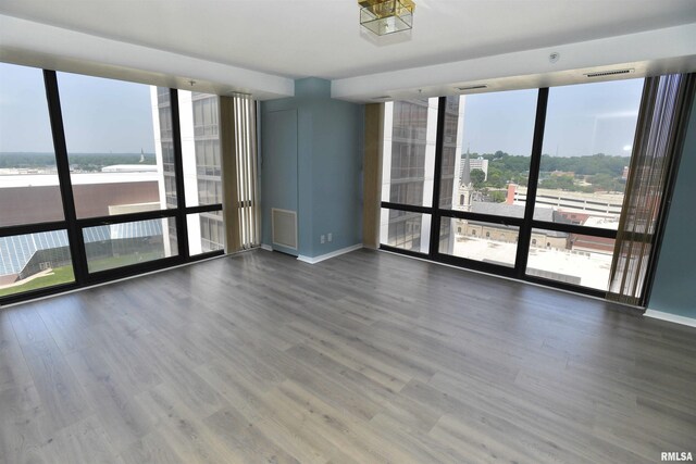 123 SW Jefferson Ave Unit E14A, Peoria, IL 61602 - empty room featuring a wall of windows, baseboards, and wood finished floors