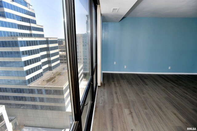 123 SW Jefferson Ave Unit E14A, Peoria, IL 61602 - unfurnished room featuring wood finished floors, a city view, baseboards, and plenty of natural light