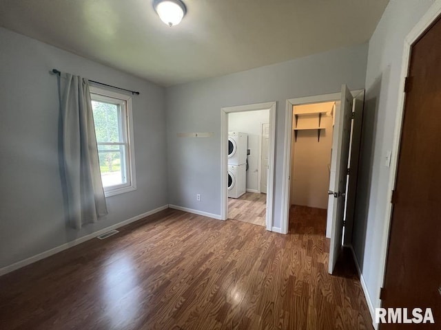 836 S Johnson St, Macomb, IL 61455 - unfurnished bedroom featuring estacked washer and dryer, a walk in closet, wood finished floors, a closet, and baseboards