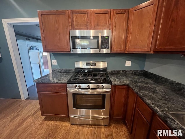 836 S Johnson St, Macomb, IL 61455 - kitchen with appliances with stainless steel finishes, light wood finished floors, dark stone countertops, and brown cabinets