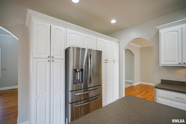 521 S French Dr, Dunlap, IL 61525 - kitchen with stainless steel refrigerator with ice dispenser, arched walkways, dark countertops, wood finished floors, and white cabinets