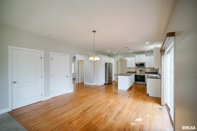 521 S French Dr, Dunlap, IL 61525 - kitchen featuring arched walkways, stainless steel appliances, dark countertops, white cabinetry, and a kitchen island