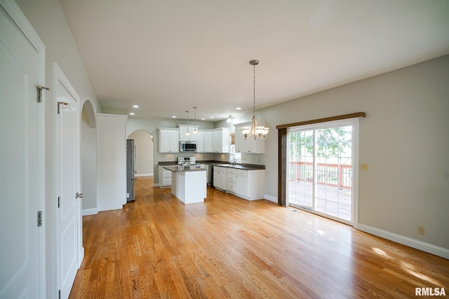 521 S French Dr, Dunlap, IL 61525 - kitchen with appliances with stainless steel finishes, arched walkways, dark countertops, a center island, and white cabinetry