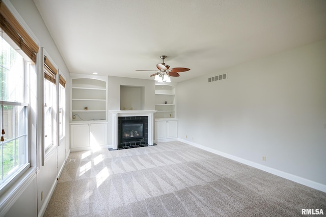 521 S French Dr, Dunlap, IL 61525 - unfurnished living room featuring light colored carpet, a fireplace, a ceiling fan, and built in shelves