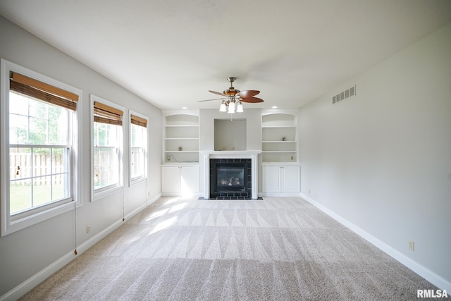 521 S French Dr, Dunlap, IL 61525 - unfurnished living room with a tiled fireplace, a ceiling fan, light carpet, and built in shelves