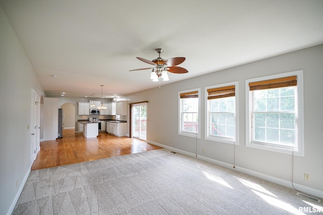 521 S French Dr, Dunlap, IL 61525 - unfurnished living room with light colored carpet, a ceiling fan, and arched walkways