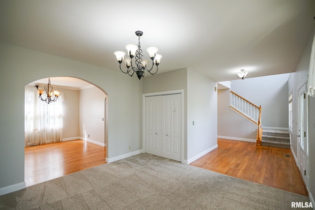 521 S French Dr, Dunlap, IL 61525 - carpeted spare room with a chandelier, arched walkways, stairway, and wood finished floors
