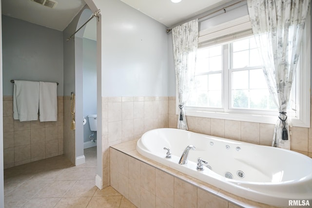 521 S French Dr, Dunlap, IL 61525 - bathroom with a tub with jets, tile walls, tile patterned floors, and wainscoting