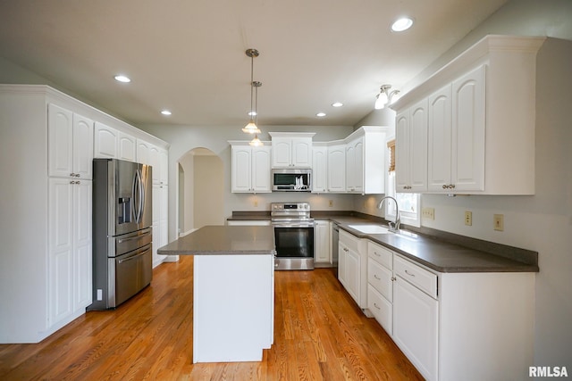 521 S French Dr, Dunlap, IL 61525 - kitchen with appliances with stainless steel finishes, dark countertops, arched walkways, a kitchen island, and white cabinetry