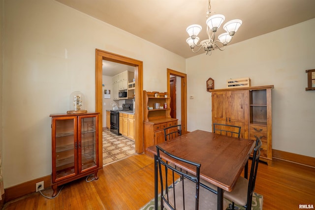602 W Adams St, Abingdon, IL 61410 - dining area featuring a chandelier, light wood-style floors, and baseboards