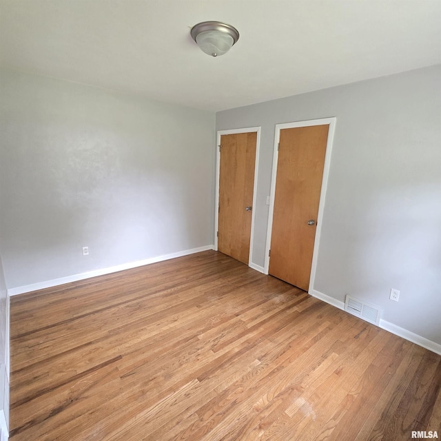 4928 W Farmington Rd, Peoria, IL 61604 - unfurnished bedroom with light wood-type flooring, baseboards, and two closets