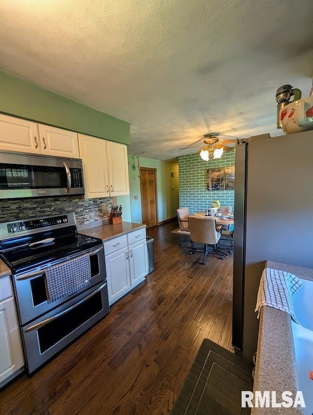 2123 Highwood Ave, Pekin, IL 61554 - kitchen featuring stainless steel appliances, white cabinets, dark wood finished floors, a ceiling fan, and decorative backsplash