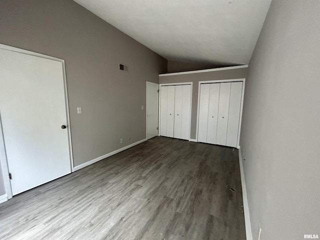 6831 N Frostwood Pkwy Unit D29, Peoria, IL 61615 - unfurnished bedroom featuring lofted ceiling, multiple closets, wood finished floors, and baseboards