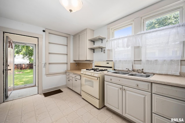 1111 S 4th St, Pekin, IL 61554 - kitchen featuring white range with gas cooktop, a sink, open shelves, and plenty of natural light
