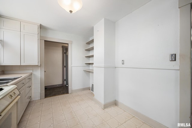 1111 S 4th St, Pekin, IL 61554 - kitchen with stove, open shelves, a sink, white cabinets, and light countertops