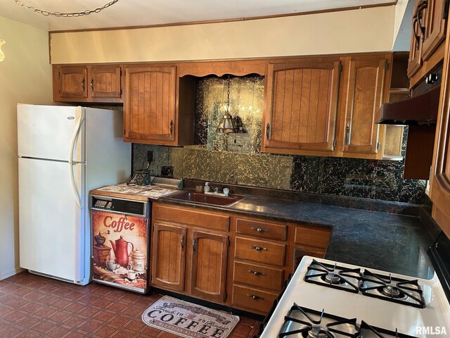 1407 Lincoln St, Pekin, IL 61554 - kitchen with freestanding refrigerator, backsplash, brown cabinetry, dark countertops, and cooktop
