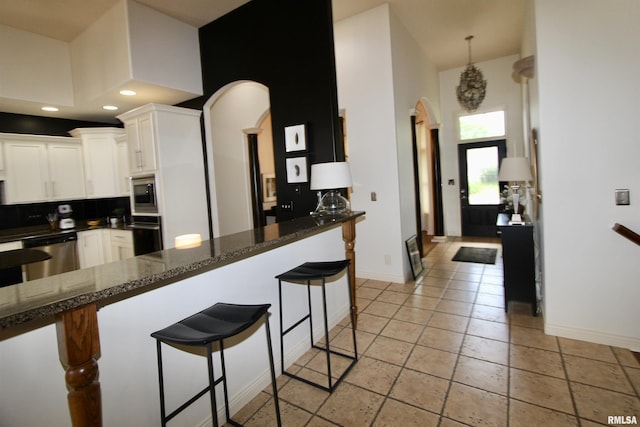 1964 Chestnut Ln, Washington, IL 61571 - kitchen featuring arched walkways, stainless steel appliances, white cabinets, a breakfast bar area, and recessed lighting