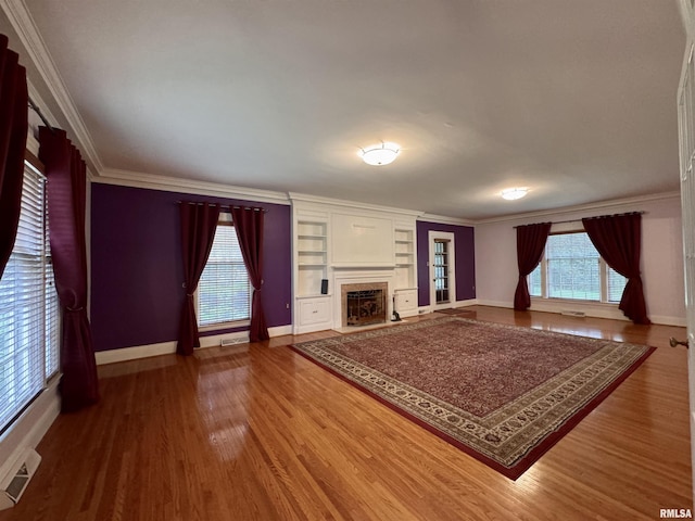 360 N Normal St, Macomb, IL 61455 - unfurnished living room featuring wood finished floors, ornamental molding, a fireplace with raised hearth, and built in features