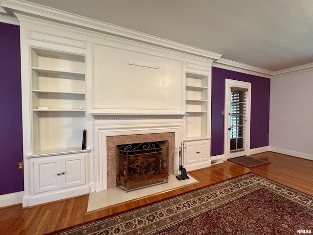360 N Normal St, Macomb, IL 61455 - unfurnished living room featuring built in shelves, ornamental molding, wood finished floors, and a fireplace with flush hearth
