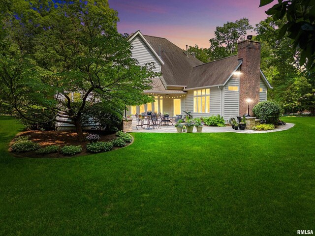 11518 N Nettle Creek Dr, Dunlap, IL 61525 - back of property featuring a patio, a chimney, a lawn, and a shingled roof